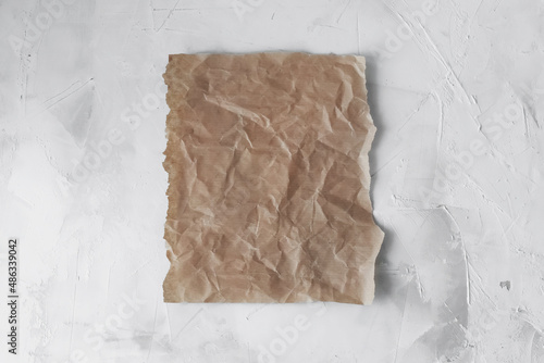 Empty space for the text . A piece of brown crumpled parchment paper on a light background.