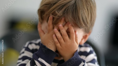 Child covering face with hands OH no
