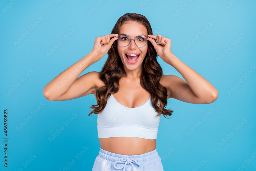 Photo of positive pretty lady open mouth omg reaction wear specs sportswear set isolated blue color background Photo of positive pretty lady open mouth omg reaction wear specs sportswear set isolated blue color background