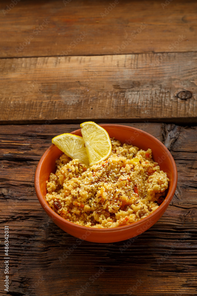 Couscous masfouf with dried fruits and nuts in a clay plate on a wooden table. Couscous masfouf with dried fruits and nuts in a clay plate on a wooden table.