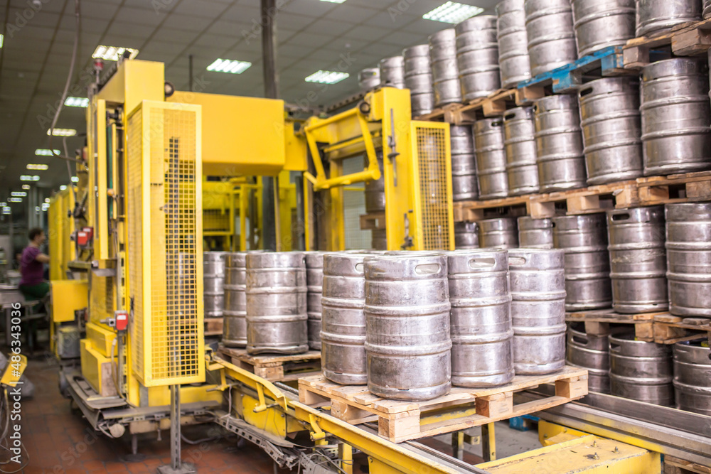 Brewery, bottling beer on aluminum kegs on conveyor lines. Industrial
