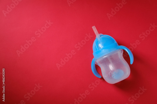 Baby bottle for drinking with water, on a red background