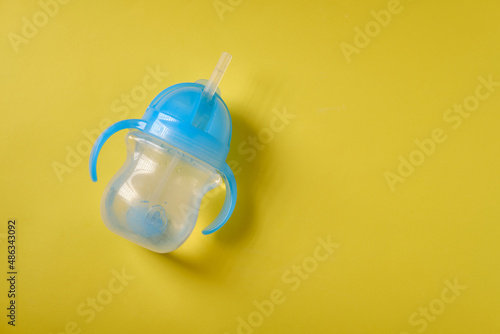 Baby bottle for drinking with water, on a yellow background
