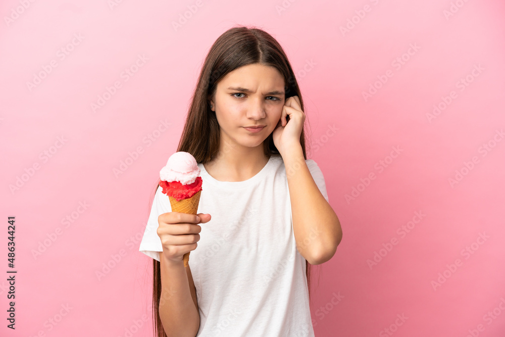 Little girl with a cornet ice cream over isolated pink background frustrated and covering ears