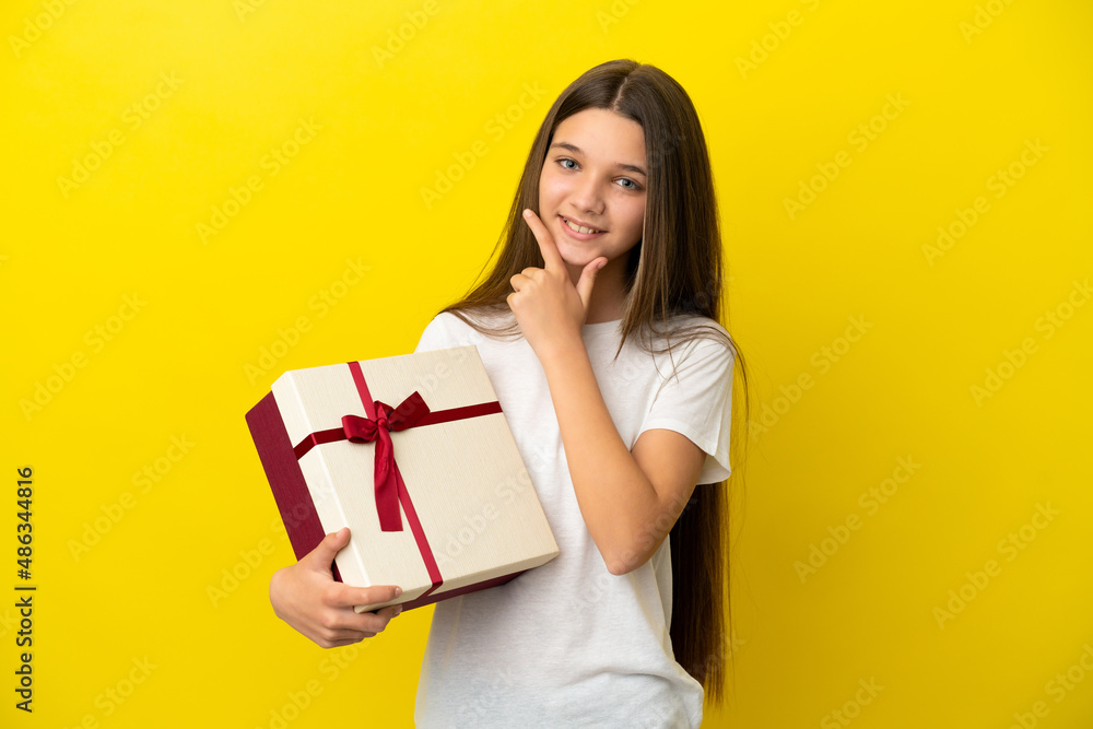 Little girl holding a gift over isolated yellow background happy and smiling Little girl holding a gift over isolated yellow background happy and smiling