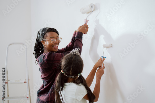 Bild auf Leinwand Mom spends time with her daughter, together they painting walls in a renovated a