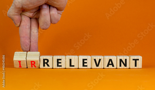 Relevant or irrelevant symbol. Businessman turns wooden cubes changes the word irrelevant to relevant. Beautiful orange table orange background. Business, relevant or irrelevant concept. Copy space. photo