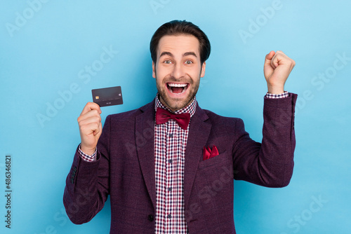 Portrait of overjoyed formalwear guy raise fists in victory triumph success hold plastic card isolated on blue color background © deagreez