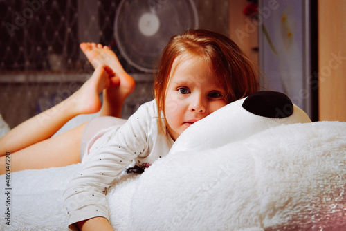 the child girl is lying on a big teddy bear photo