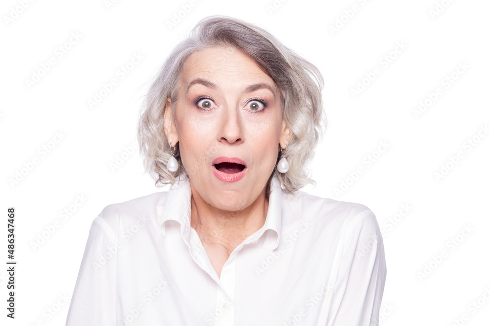 An adult, mature, beautiful woman looks very surprised and impressed by what she saw, looking at camera with her mouth and eyes wide open, isolated on white background An adult, mature, beautiful woman looks very surprised and impressed by what she saw, looking at camera with her mouth and eyes wide open, isolated on white background