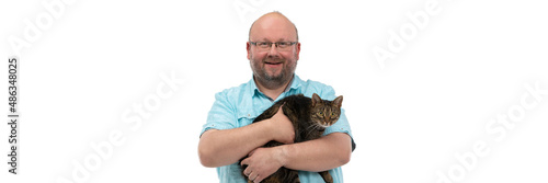 Bald man holds she-cat in his arms and smiles. Panoramic frame.