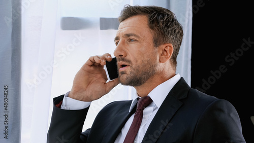 businessman in formal wear talking on smartphone in office
