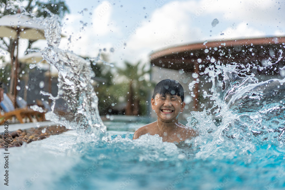 Obraz premium Asian Young Boy Having a good time in swimming pool, He Jumping and Playing a Water in Summer.