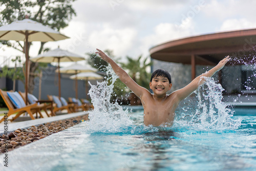 Asian Young Boy Having a good time in swimming pool  He Jumping and Playing a Water in Summer.