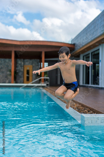 Asian Young Boy Having a good time in swimming pool, He Jumping and Playing a Water in Summer. © Songkhla Studio