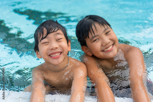 Asian Young Boy Brother Having a Good Time Playing and Enjoying in Swimming Pool Together in Summer