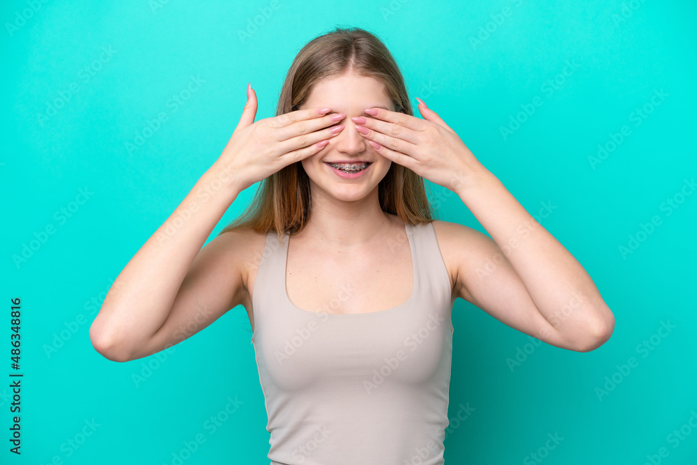 Teenager Russian girl isolated on blue background covering eyes by hands and smiling Teenager Russian girl isolated on blue background covering eyes by hands and smiling