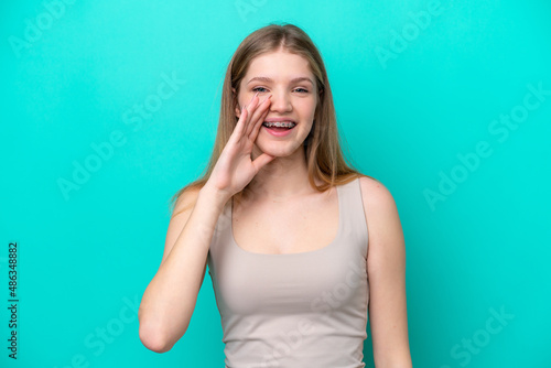 Teenager Russian girl isolated on blue background shouting with mouth wide open