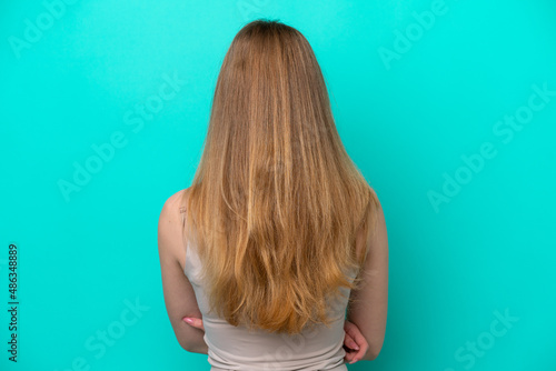 Teenager Russian girl isolated on blue background in back position