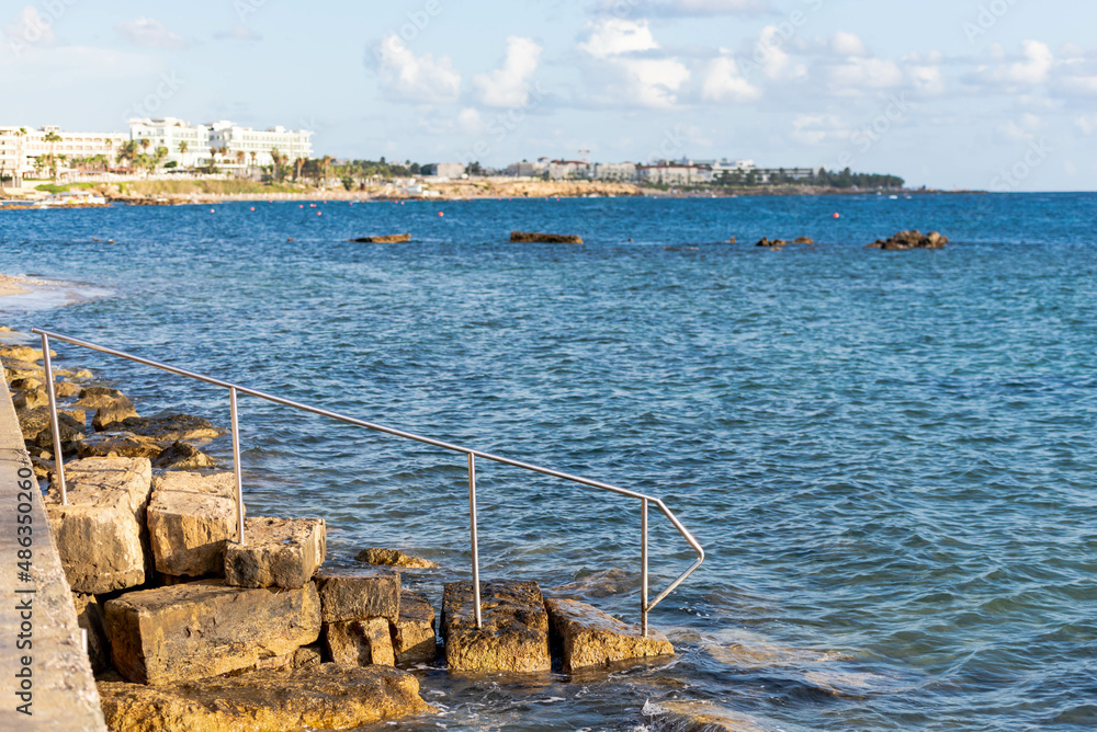 Descent into the sea from stone steps. Turquoise sea at the waterfront of the city of Paphos in Cyprus in autumn. Descent into the sea from stone steps. Turquoise sea at the waterfront of the city of Paphos in Cyprus in autumn.