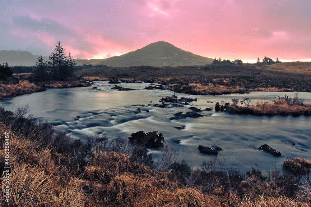 Beautiful orange sunrise landscape scenery with river stream and mountains at Derryclare natural reserve in Connemara National park, county Galway, Ireland 