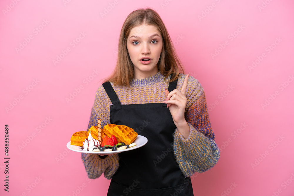 Teenager Russian girl holding a waffles isolated on pink background intending to realizes the solution while lifting a finger up