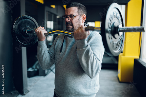 Middle aged man lifting barbell in the gym