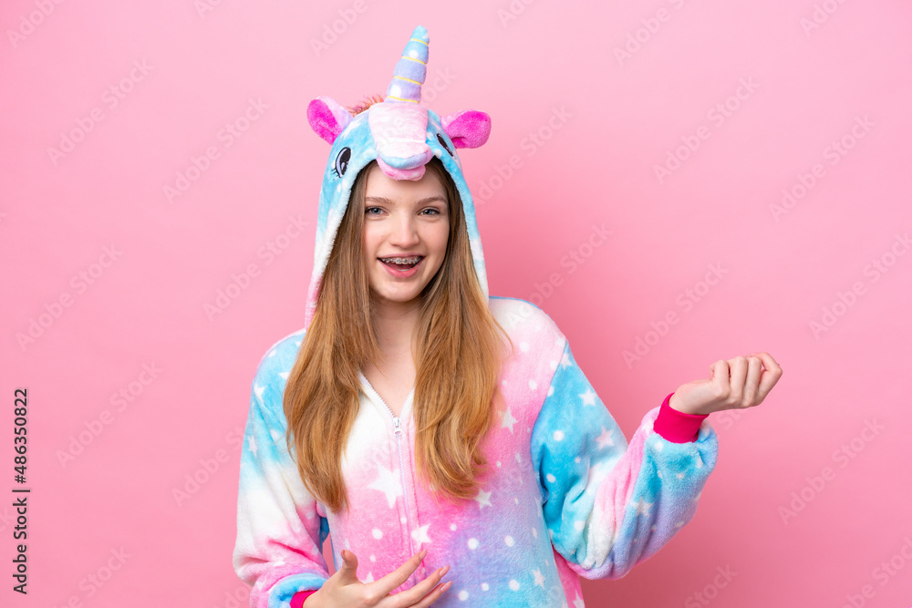 Teenager Russian girl with unicorn pajamas isolated on pink background making guitar gesture Teenager Russian girl with unicorn pajamas isolated on pink background making guitar gesture