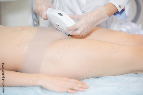 Close up shot of a girl on a cosmetology chair during the procedure of laser hair removal of the bikinia zone
