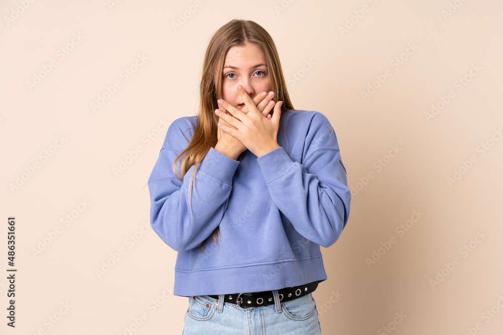 Teenager Ukrainian girl isolated on beige background covering mouth with hands Teenager Ukrainian girl isolated on beige background covering mouth with hands