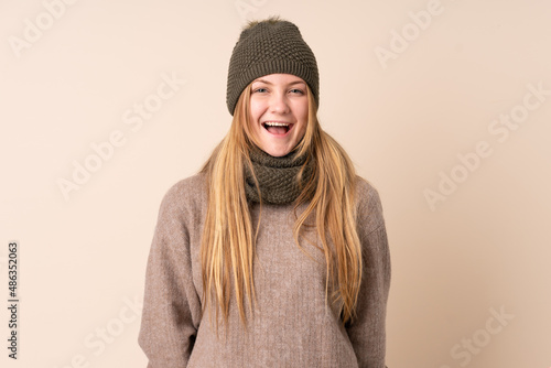 Teenager Ukrainian girl with winter hat isolated on beige background with surprise facial expression © luismolinero