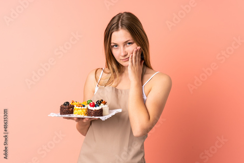 Pastry Ukrainian chef holding a muffins isolated on pink background unhappy and frustrated