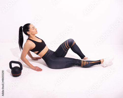 Strong fitness woman sitting on the floor isolated on white