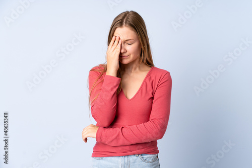 Teenager Ukrainian girl isolated on blue background with headache