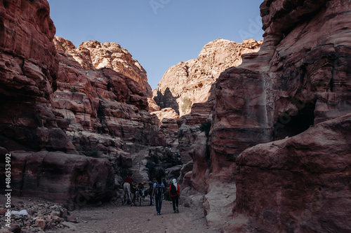 Ruins of the ancient city of Petra in Jordan. Red sandstone mountains on a clear day. Caves in the rock. Tourists in Petra. Colorful photos.