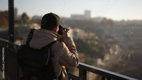 Photographer tourist traveler man stands on bridges and makes photos. European tourism, people sightseeing traveling. Pictures making by male traveler. Autumn weather in Europe. Outdoor cityscape view photo