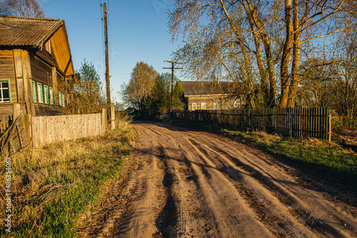 Country dirt road with deep gauge on the spring sunset. Russian village