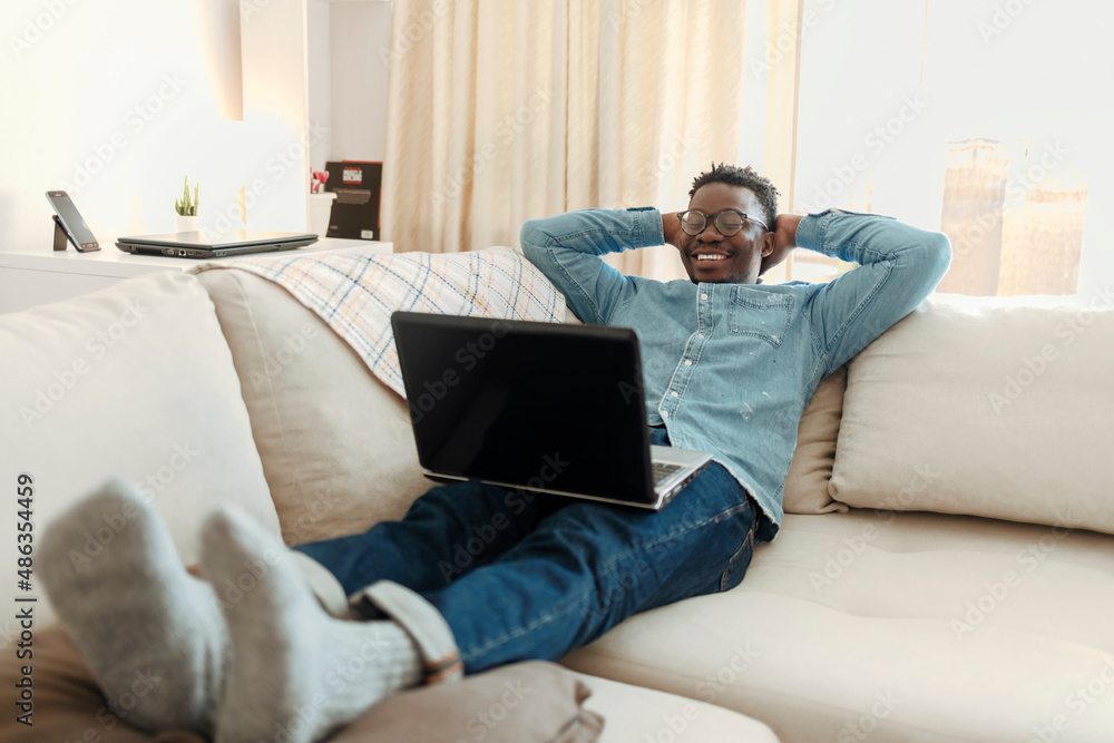 Photo of a young man using a laptop while relaxing at home. Cropped shot of a handsome young man using his laptop while chilling on the sofa at home. Photo of a young man using a laptop while relaxing at home. Cropped shot of a handsome young man using his laptop while chilling on the sofa at home.