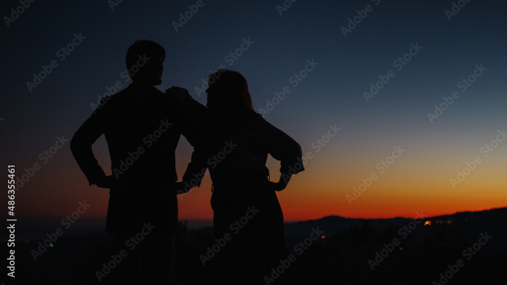 Silhouette of boy and girl hug each other at sunset 
