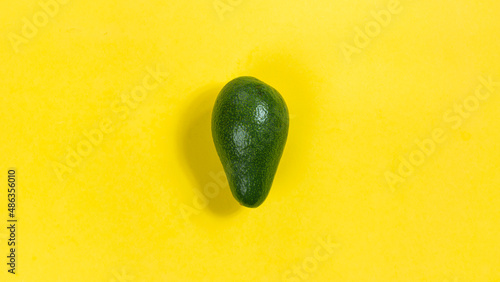 Green ripe avocado on a yellow background close-up.