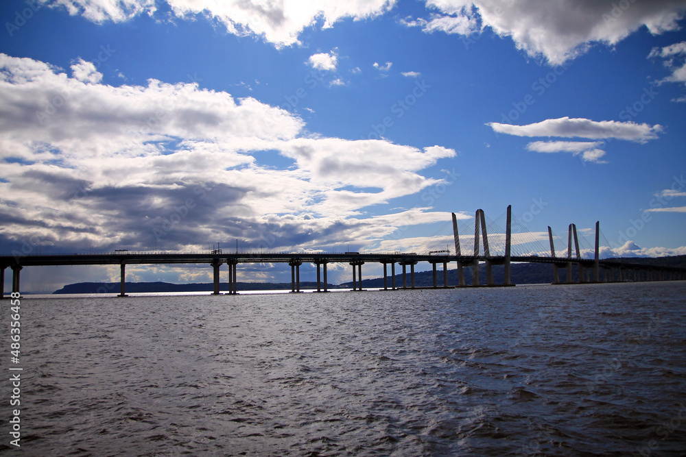 The long Governator Cuomo Bridge with clouds and blue sky on the Hudson river