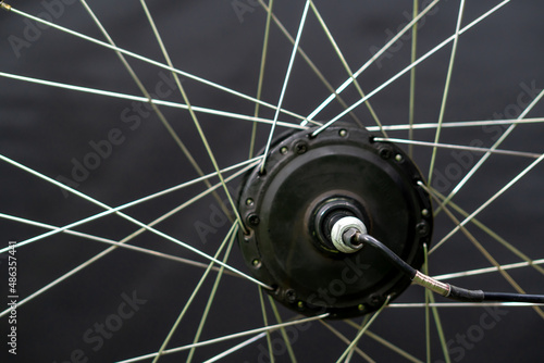Repair of electric bicycles. Bicycle wheel, spokes and electric motor close-up on a black background.