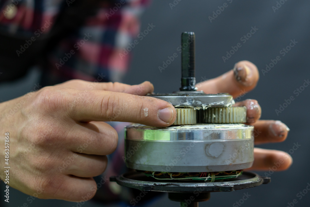 Repair of a bicycle electric motor. The disassembled motor is installed in a vise for maintenance, grease replacement, gear cleaning.