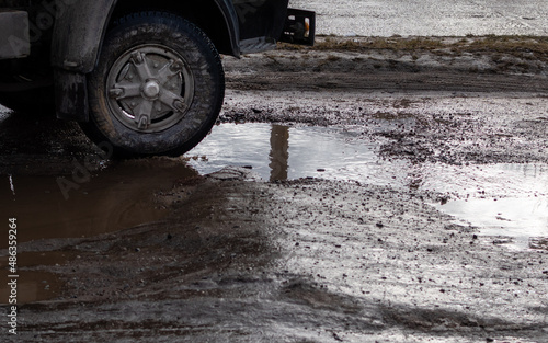 Front wheel of a truck close-up in muddy puddle of broken road