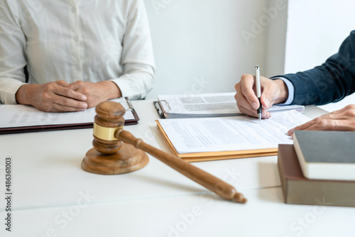 Male lawyer is pointing on legal document to explaining about consultation terms and condition to businesswoman before signing on contract at law firm