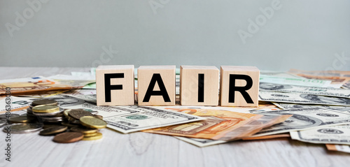 FAIR inscription on the texture of wooden cubes. Wooden cubes on the background of banknotes. An inscription on a financial, business or economic theme.