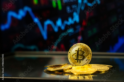 Pile of bitcoins with stock market statistics graph background. Crypto currency growth in world e-commerce banking system financial concept