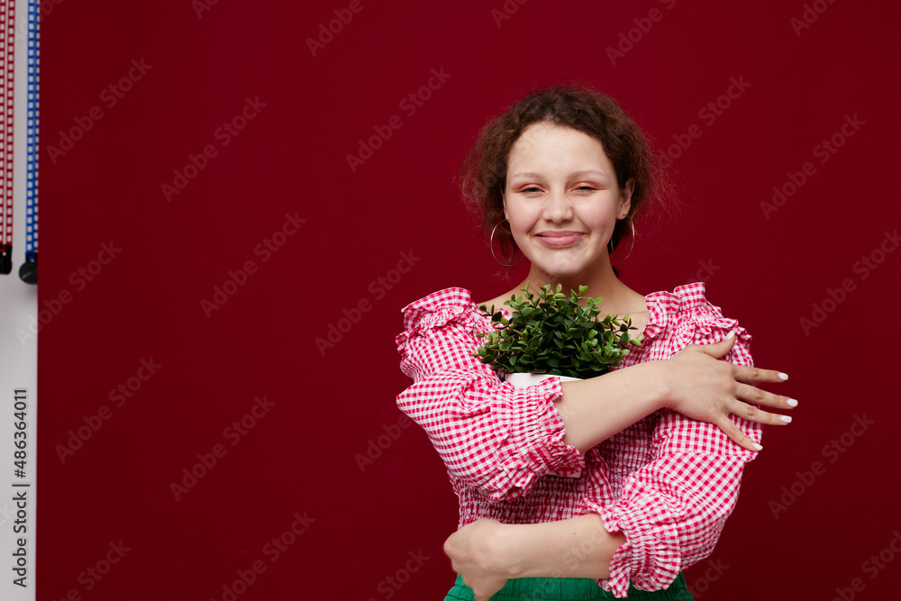 cheerful woman with a flower in a pot in her hands red background unaltered cheerful woman with a flower in a pot in her hands red background unaltered