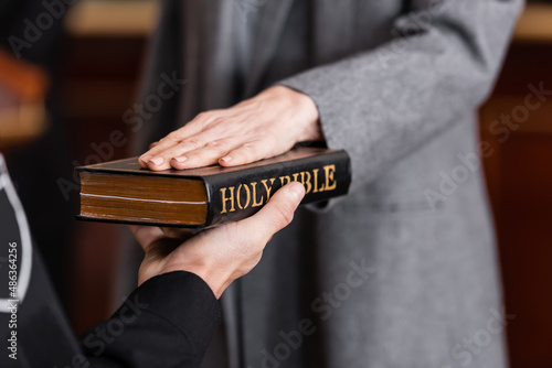 Foto partial view of bailiff holding bible near woman giving swear in court