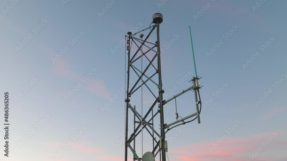 Cell tower with multiple 5G, 4G & LTE antennas and radio dishes. Close-up video from drone with tower against evening sky. Cell tower with multiple 5G, 4G & LTE antennas and radio dishes. Close-up video from drone with tower against evening sky.